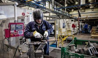  Waupaca Foundry employee inspects iron castings as they make their way through the mill room